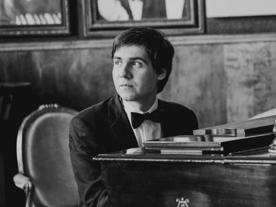Vadym Kholodenko sits at a Steinway piano and gazes thoughtfully to the side