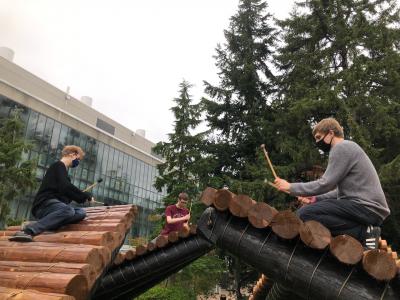percussions use cloth mallets on a sculpture made of peeled logs