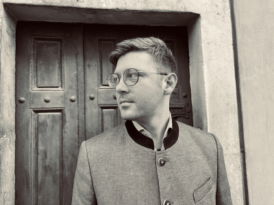 Daniel Adam Maltz in front of an old door, dressed smart, looking to the side