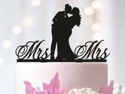 cake topper depicting a couple kissing with the words "Mrs" and "Mrs" on either side.