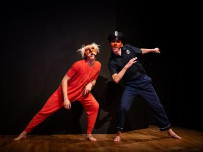 two masked performers, one in red long underwear, the other dressed as a police officer
