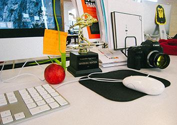 desk with computer, mouse, apple, camera