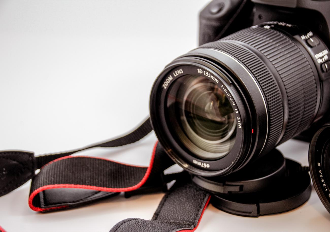 close-up view of an SLR camera resting on a white surface with its lens cap off
