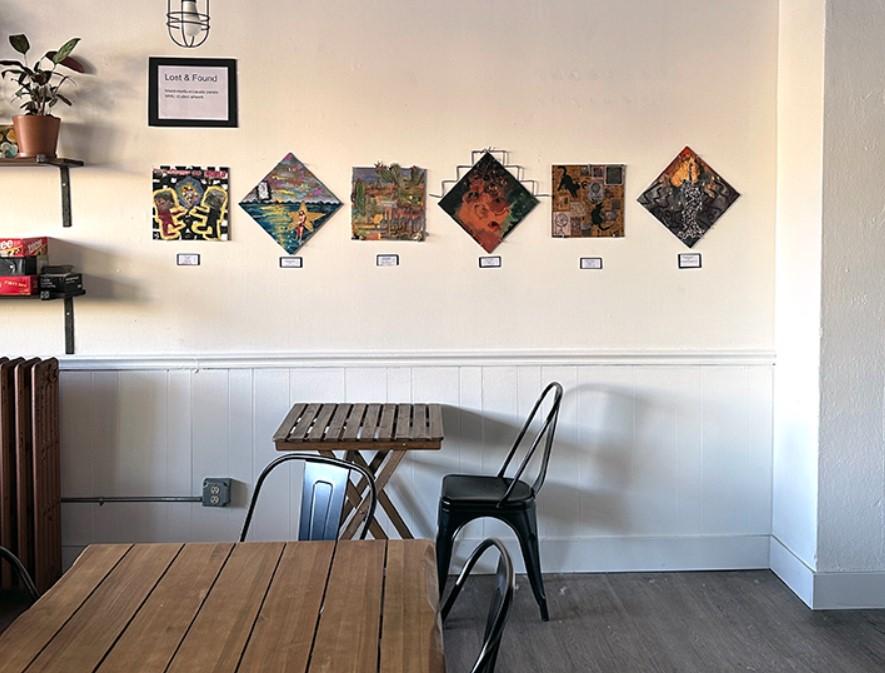 empty dining tables and chairs set up in front of a wall decorated with square and diamond shaped art pieces