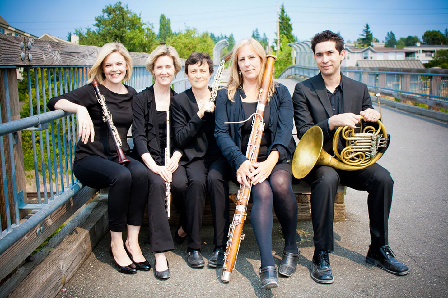 members of ensemble holding clarinet, flute, oboe, bassoon, horn