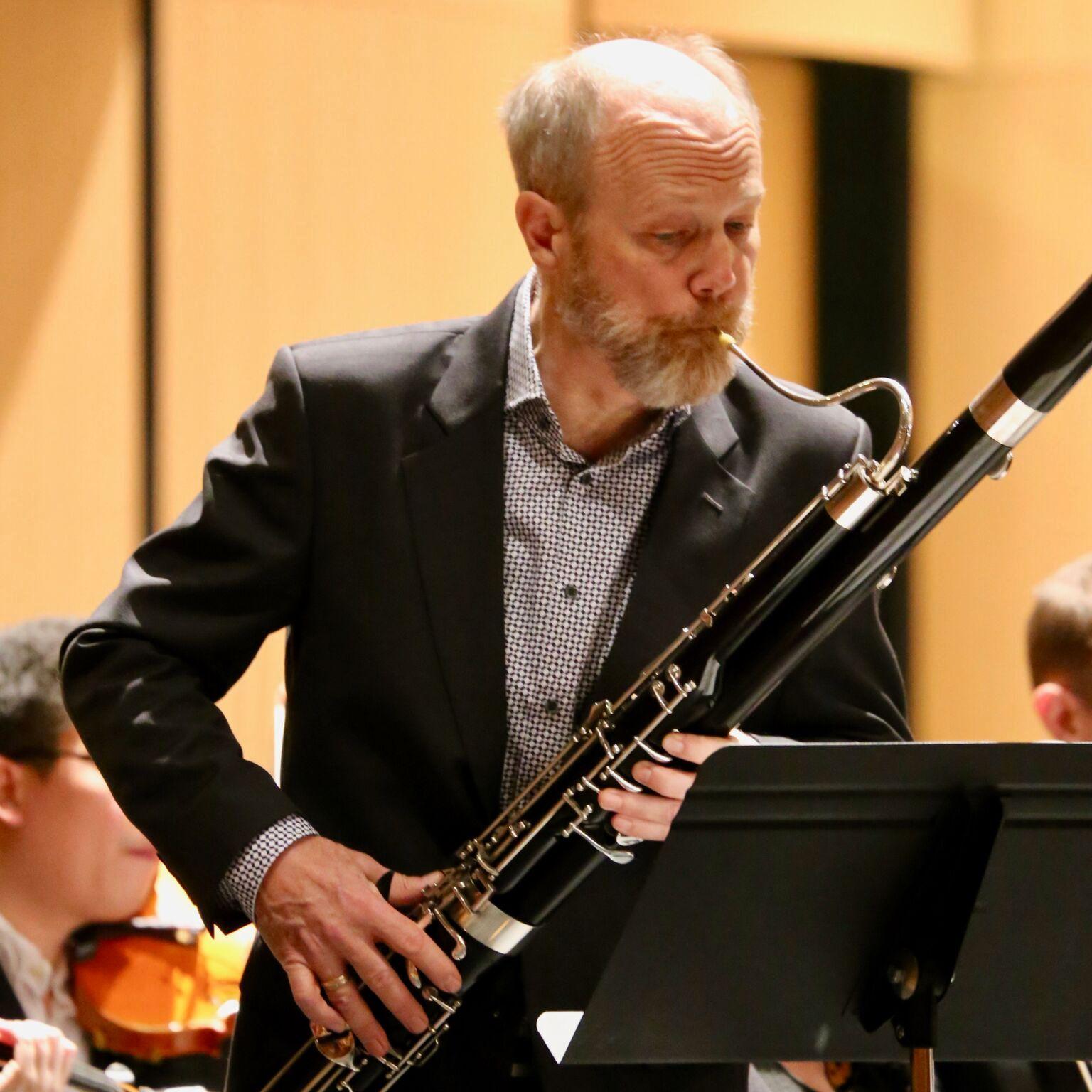man with beard blows into a bassoon