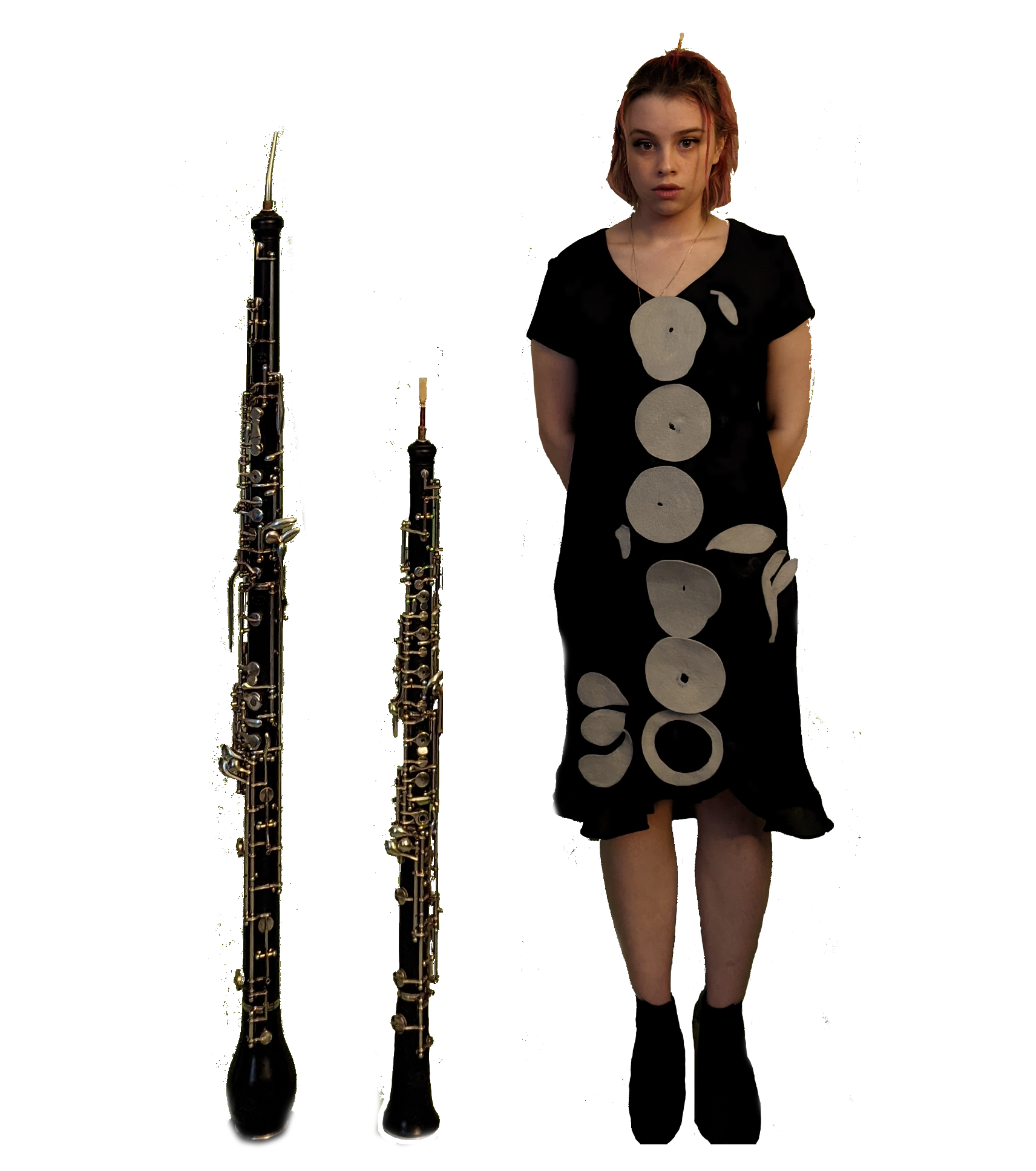 Katarina Freedman standing next to two wind instruments. One is taller than Katarina's elbow, and one is almost as tall as Katarina.