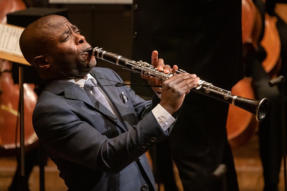 Anthony McGill in a suit, leaning back with eyes closed, playing clarinet