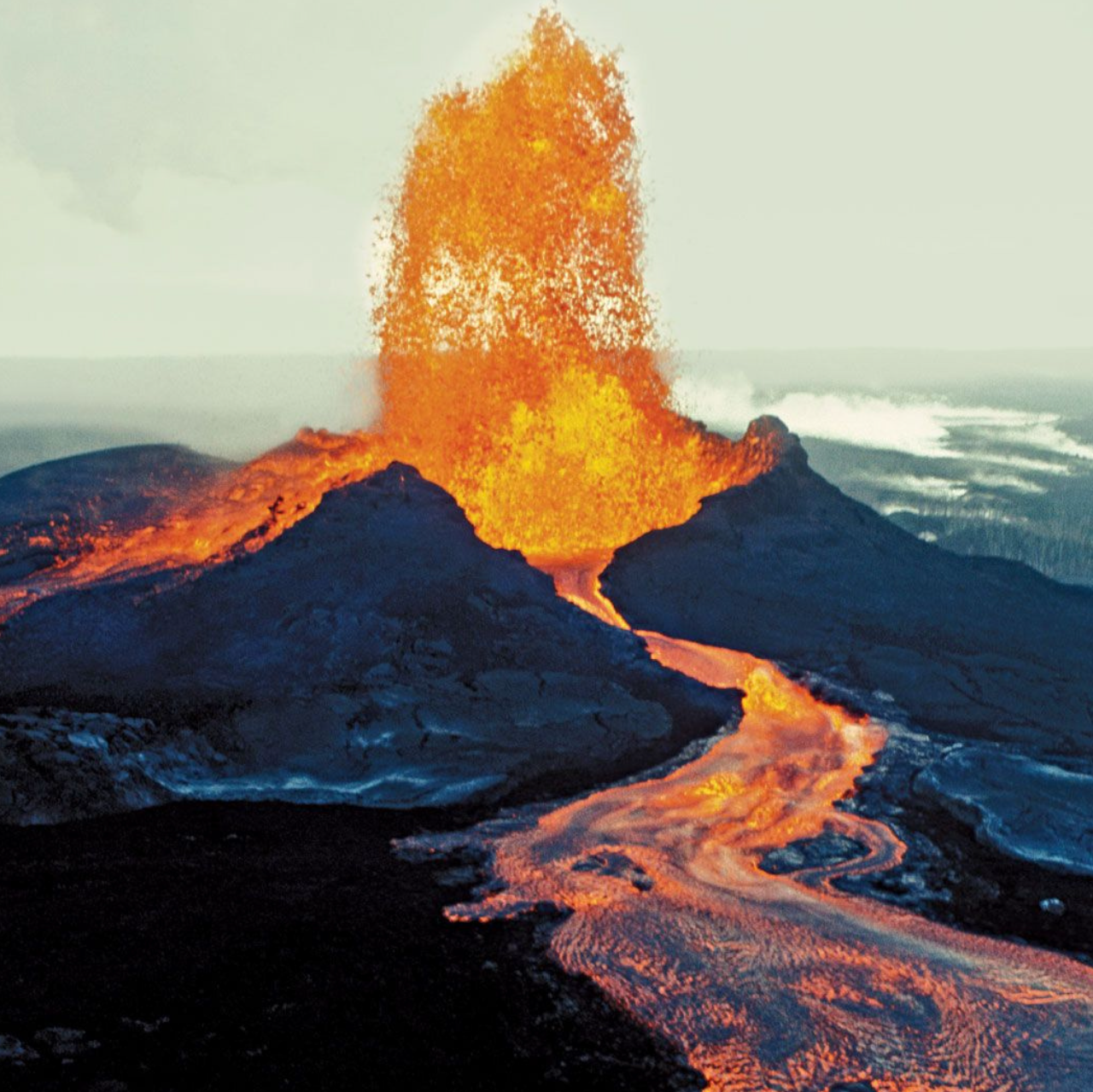 Lava errupts out of a volcano like a geyser and meanders down the mountain