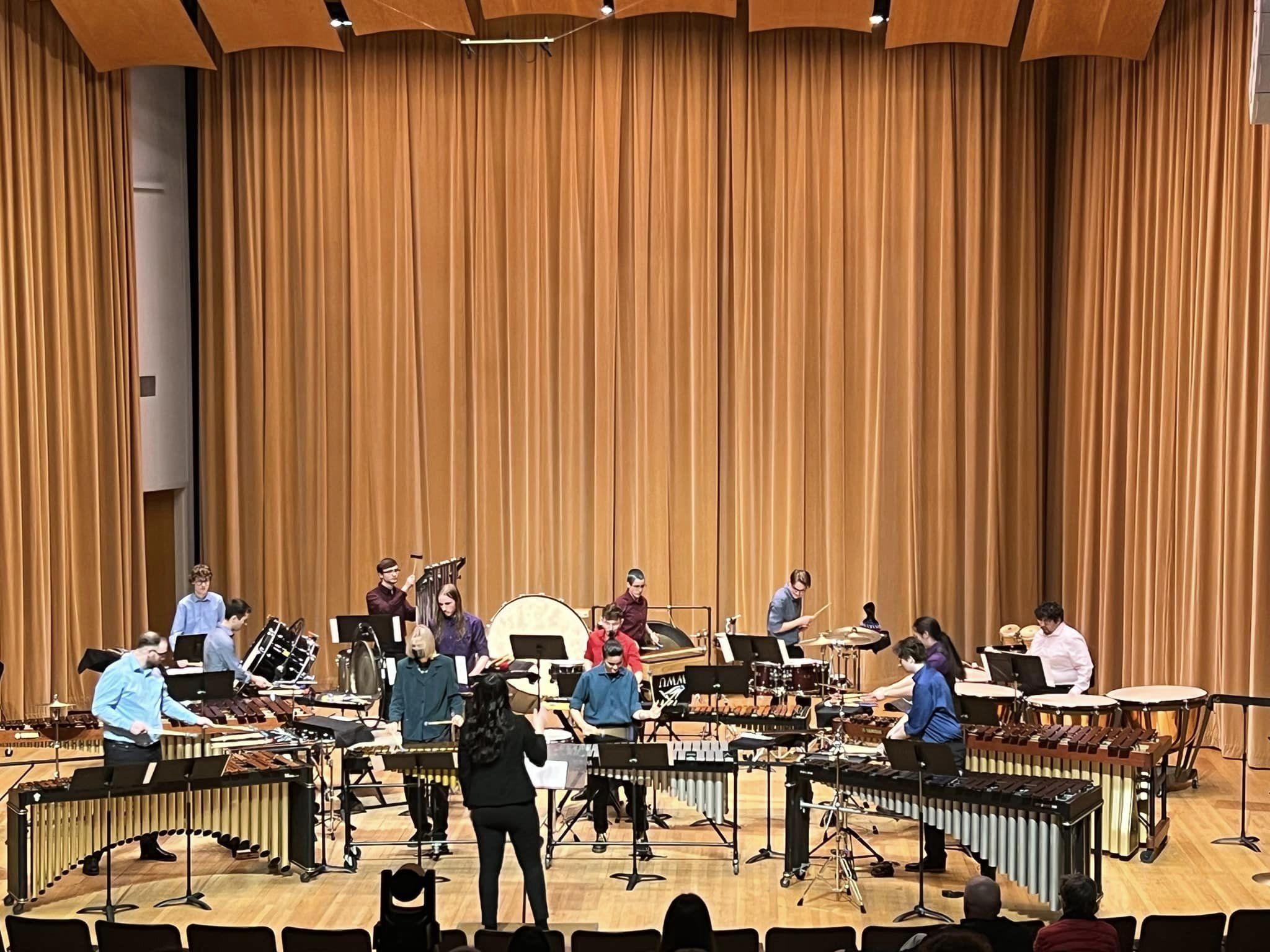 a dozen percussionists on stage surrounded by marimbas, drums, and all manner of percussion instruments.