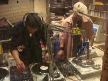 Two hip hop DJs creating new music by mixing tracks from multiple record players