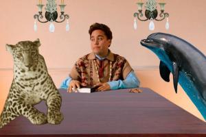 Chris Vargas sits at a dining table with a cheetah and a dolphin