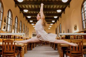 dancer leaping as between tables in an ornate library reading room