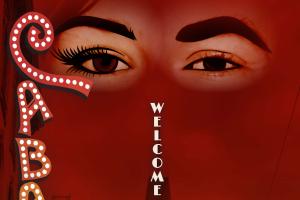 A pair of eyes - one side feminine, the other masculine - float in a blood red sky gazing over tower in a Berlin skyline. The words "Welcome to Berlin" are imposed vertically over the tower. "Cabaret (1998 version)" is spelled down the side of the image in whimsical marquee style lettering.