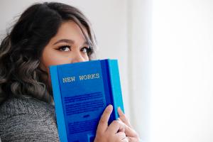 A person peers over a book titled "New Works"