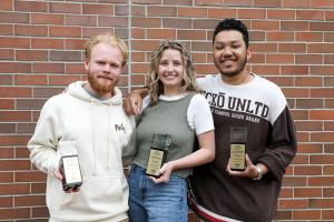 three design students holding trophies