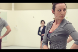 a dancer in grey turns at the waist and looks over her shoulder