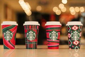 4 coffee cups in a row with various design patterns akin to wrapping paper, and the Starbucks logo