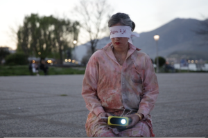 a person sitting in an empty parking lot, blindfolded