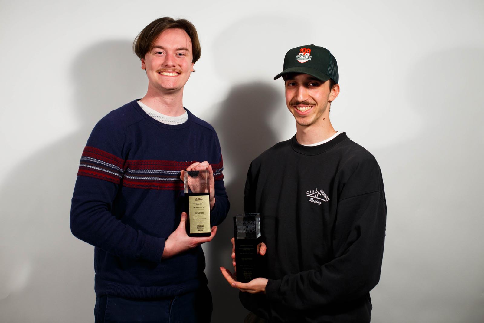 two student designers hold their design trophies