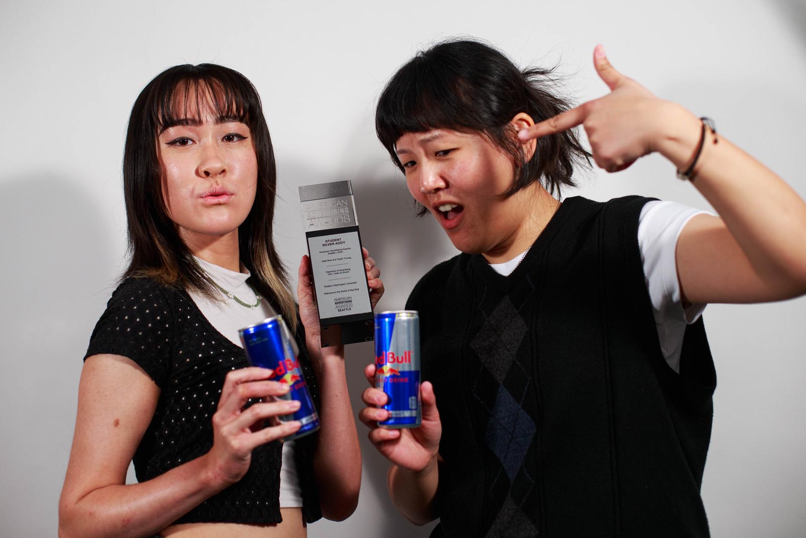 two design students hold a trophy and cans of Red Bull