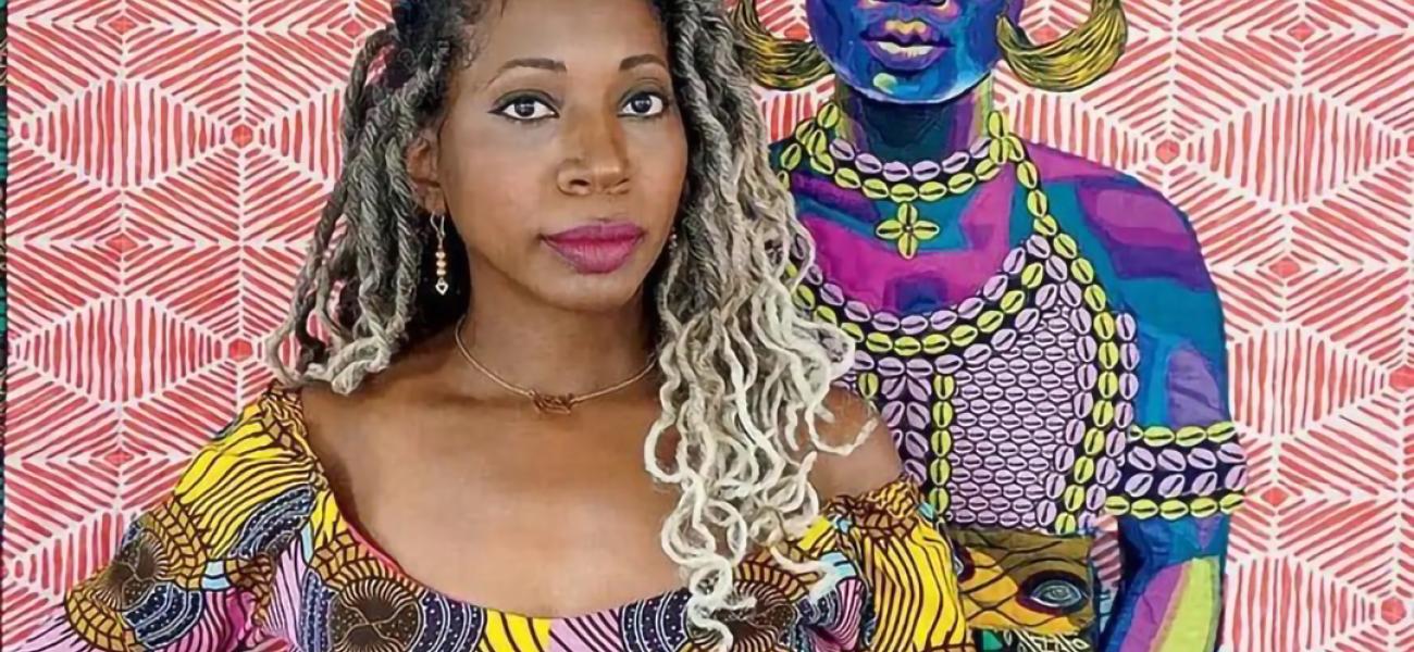Portrait of artist Bisa Butler with a straight face and hands on hips, wearing a bright geometric-patterned top, in front of her quilted work depicting a woman in tribal African attire.