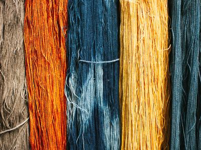 full frame shot of rich, natural colors of dyed yarn, displayed side by side in stripes of loose thread.