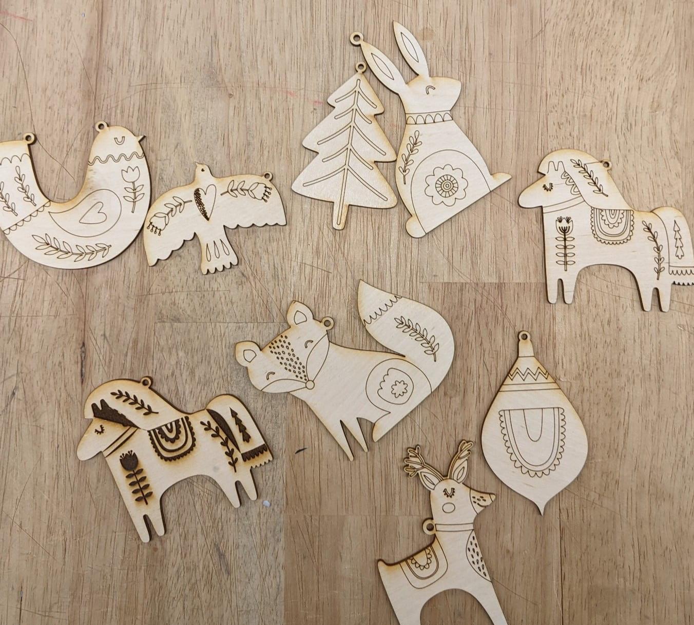 flat wood ornaments in animal and tree shapes with lasercut designs on them
