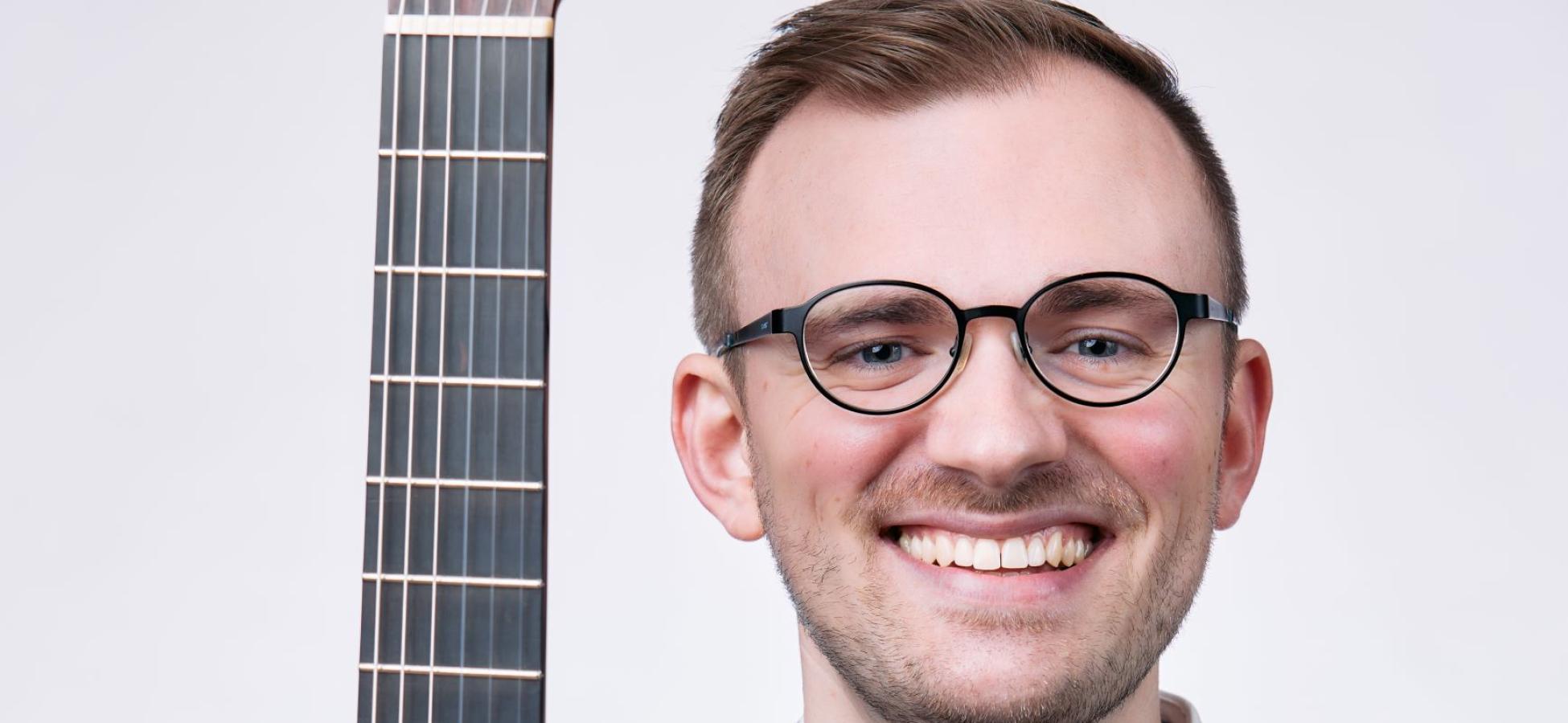 a person smiling holding a guitar