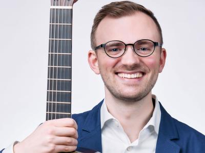 a person smiling holding a guitar