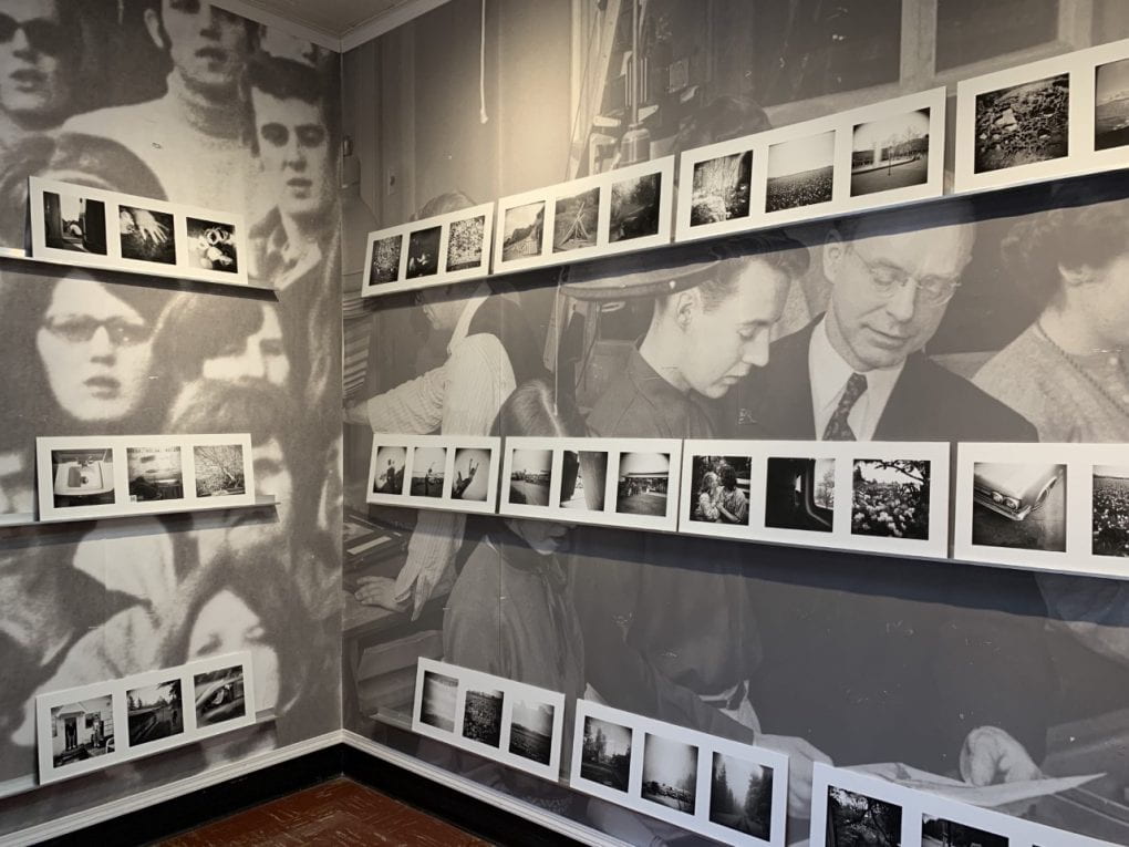 A series of black and white photos display in rows in a corner