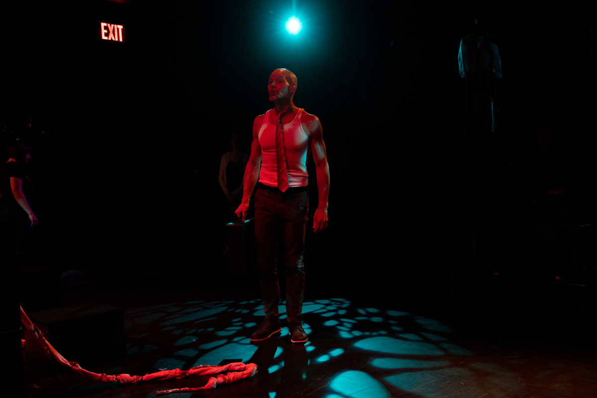 a person in a darkened place stands illuminated by a dim red light