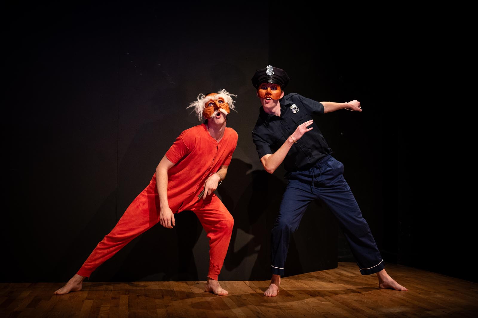 two masked performers, one in red long underwear, the other dressed as a police officer