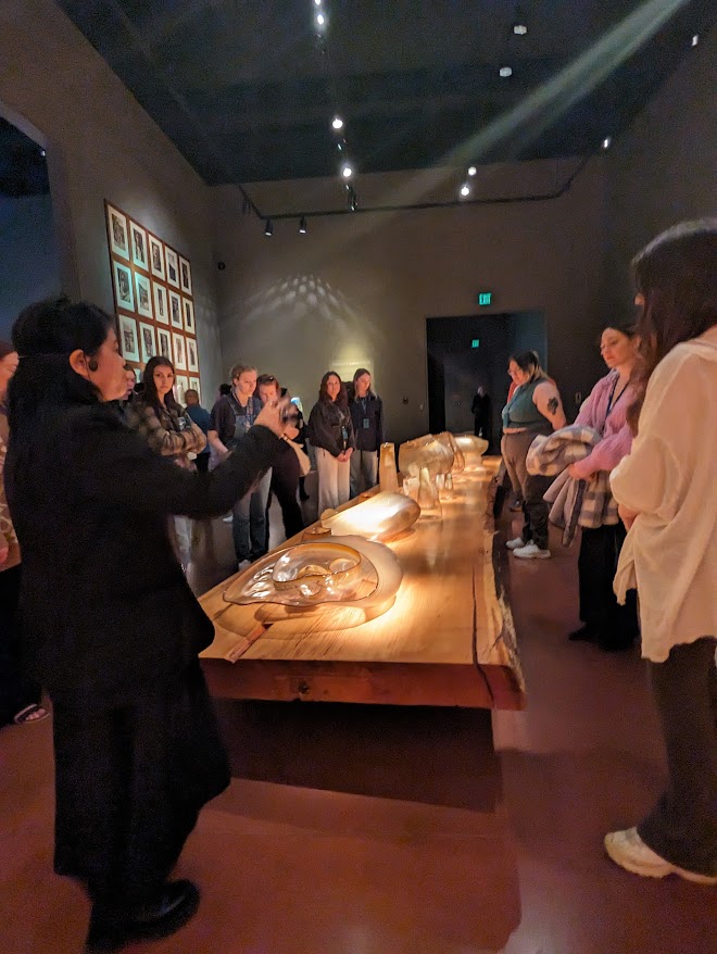 a person at the head of a long table makes remarks to a group