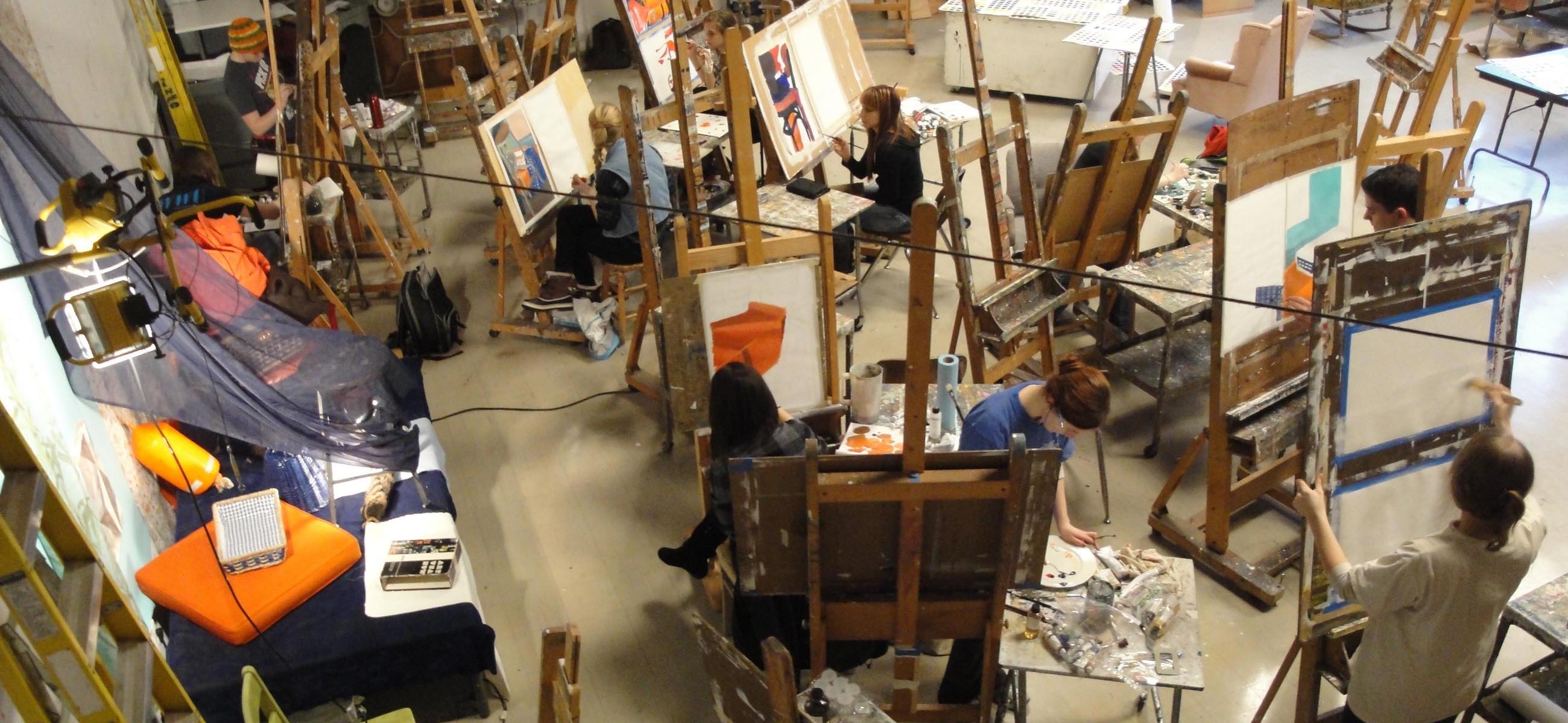 an overhead view of a large painting studio crowded with easels and cluttered with painting tools