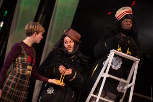 a young person is offered assistance by two actors in crow costumes